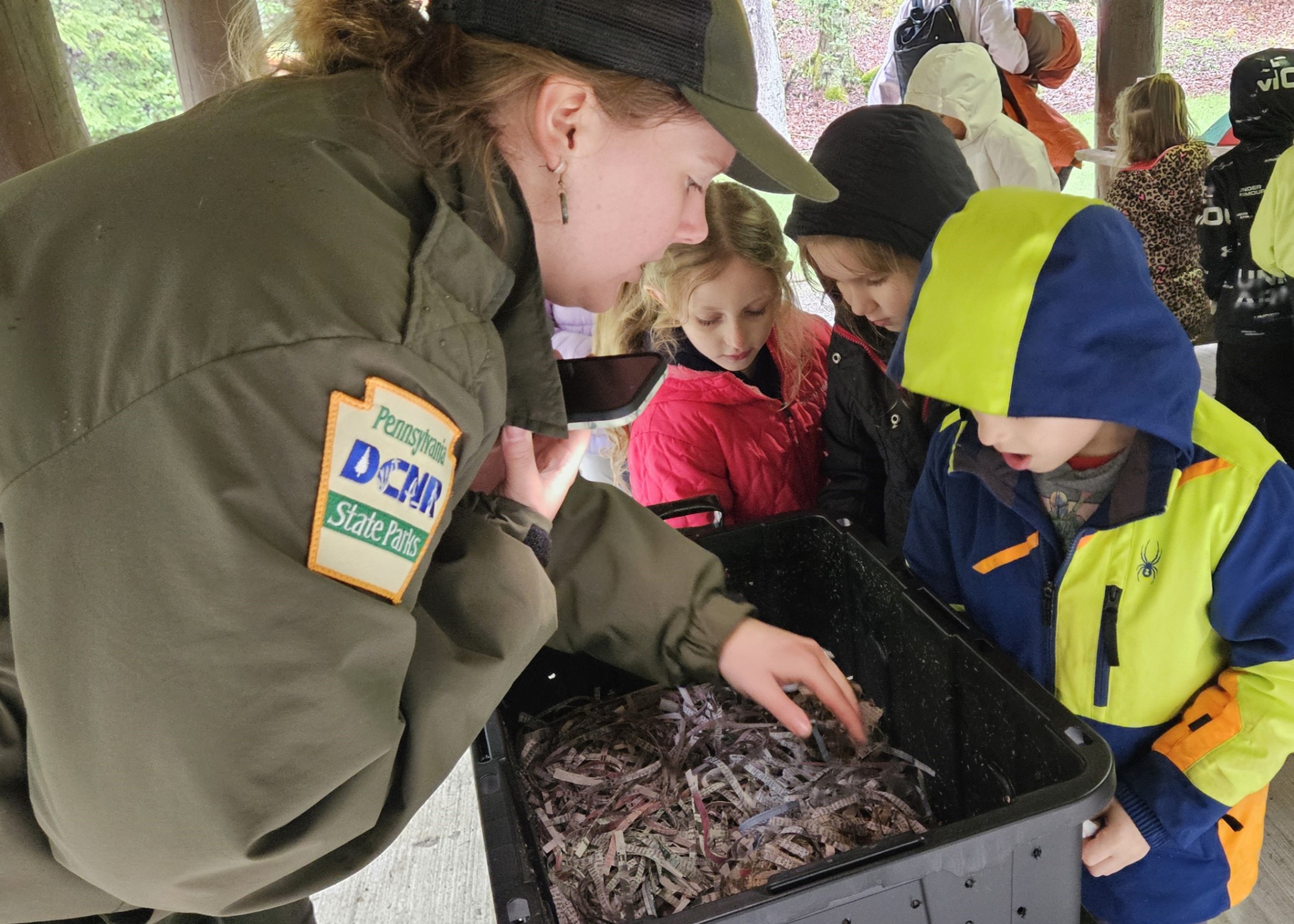 Jenna Hyde from DCNR shows three kindergarten students some critters at Clear Creek State Park.